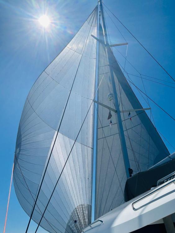 2024 Excess 14 sailboat with full sails under bright sun and clear blue sky.
