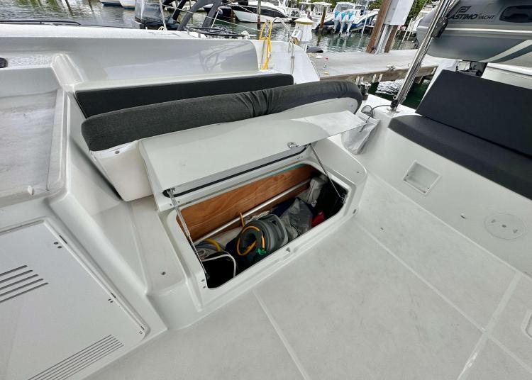 2023 Lagoon 46 yacht storage compartment with open hatch, revealing interior equipment and seating area.