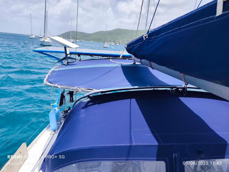 Beneteau Cyclades 43.3 sailboat with blue canopy on clear turquoise water, 2005 model.