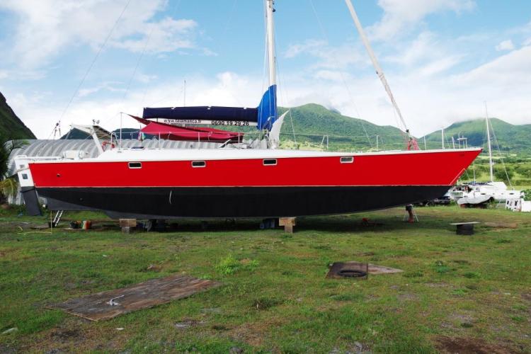Red and black 1995 Catamaran Day Charter Open Bridge Deck on land, scenic mountain backdrop.