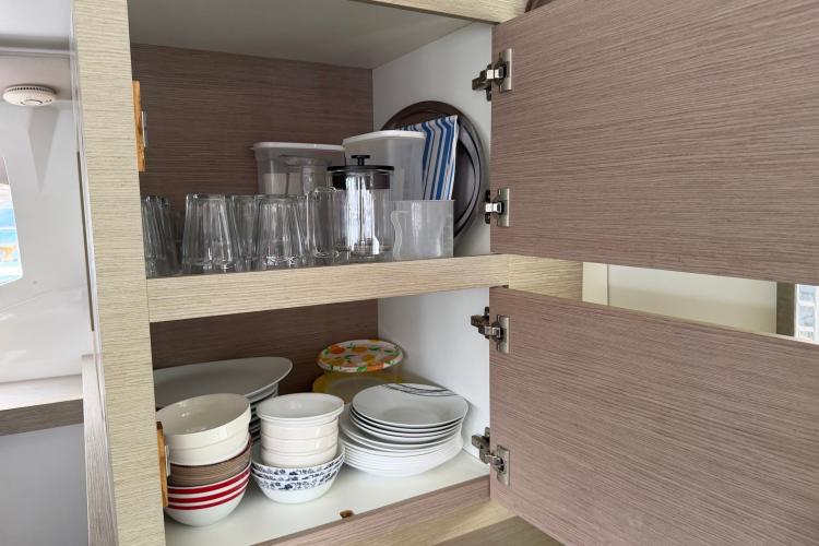 Cabinet interior on 2020 Fountaine Pajot Astrea 42, featuring neatly arranged dishes and glasses.
