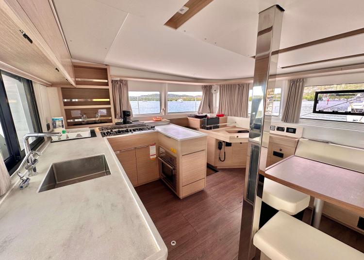 Modern interior of 2023 Lagoon 46 yacht with kitchen and dining area.