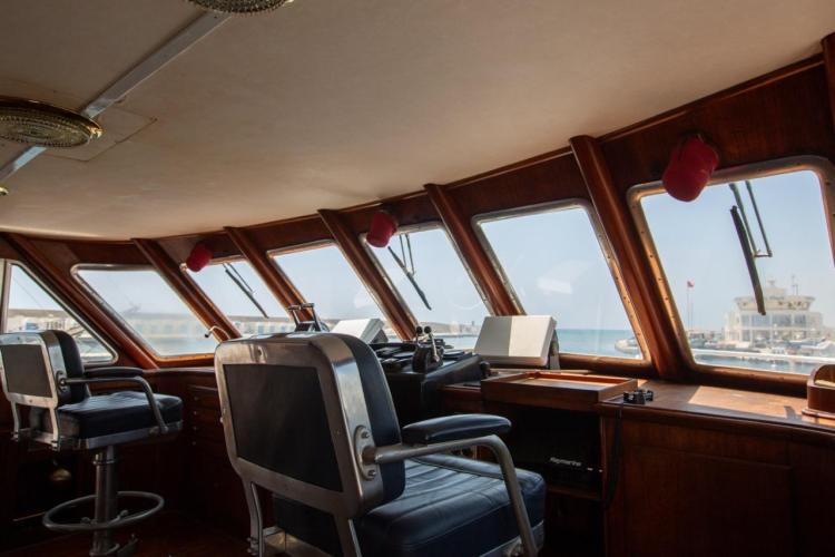 Interior of 1972 Benetti 33 yacht's helm with panoramic windows and captain's chairs.