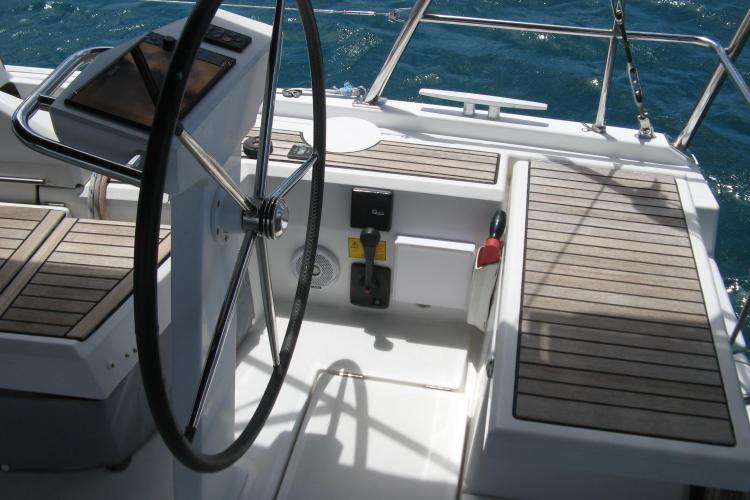 Cockpit of 2019 Beneteau Oceanis 46.1 sailboat with wooden seating and steering wheel.