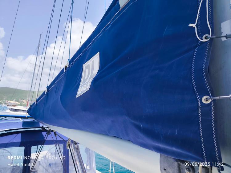 Blue sail cover on a 2005 Beneteau Cyclades 43.3 yacht, sunny day, marina background.