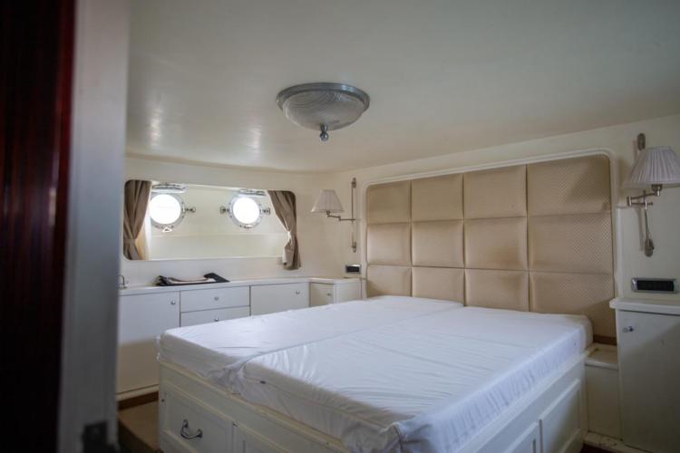 Luxurious bedroom interior of 1972 Benetti 33 yacht with porthole windows and elegant decor.