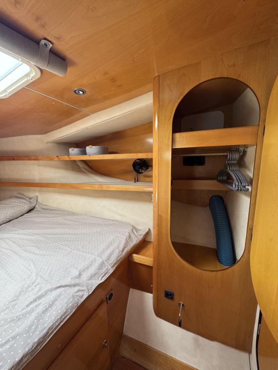 Interior cabin of 2006 Fountaine Pajot Bahia 46 catamaran, featuring wooden shelves and cozy bedding.