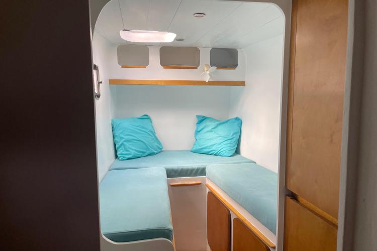 Compact cabin interior with turquoise cushions, wooden accents, and modern design in Custom KSENIA 149, 2010.