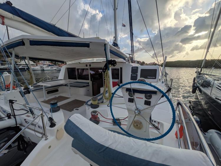 2012 Catana 55 yacht cockpit with steering wheel, docked at marina during sunset.