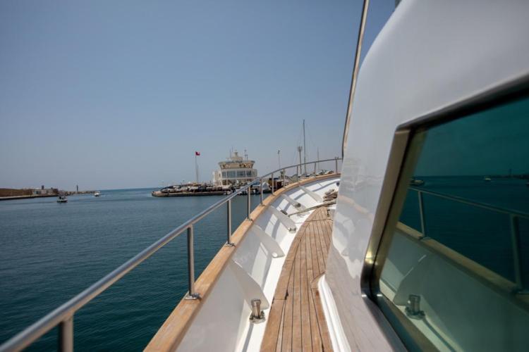 1972 Benetti 33 yacht cruising near a harbor under clear blue skies.