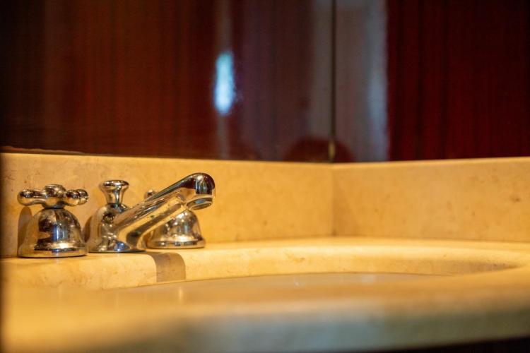 Chrome faucet on marble sink in 1972 Benetti 33 yacht bathroom.