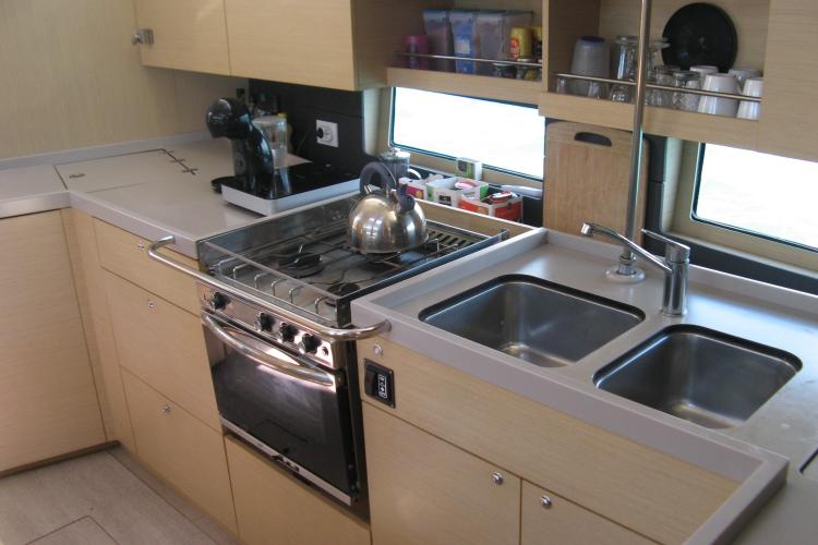 Modern kitchen in 2019 Beneteau Oceanis 46.1 yacht with stove, sink, and storage.
