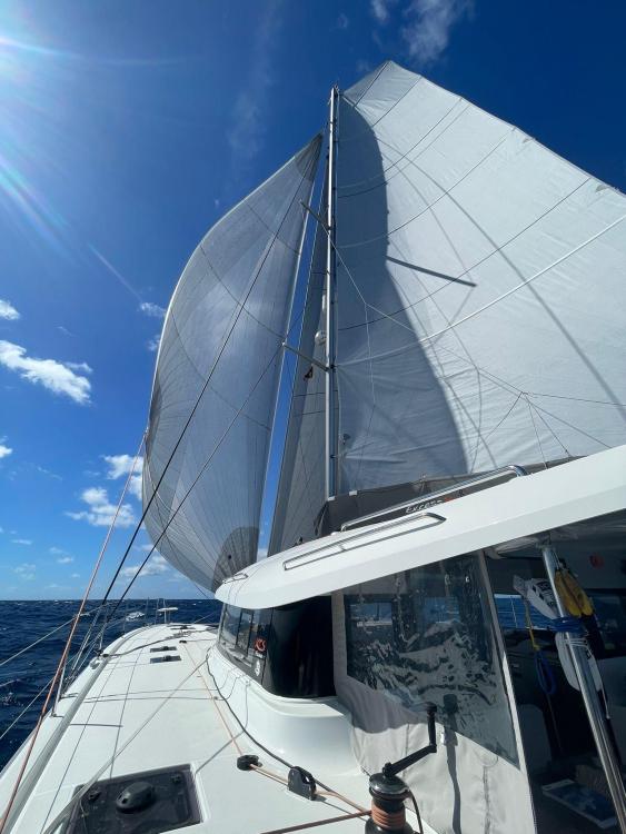2024 Excess 14 sailboat with full sails under a clear blue sky.