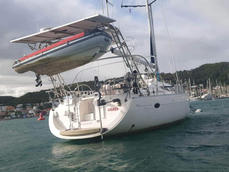 Sailboat Elan Impression 434 (2007) with dinghy, anchored in a scenic harbor.