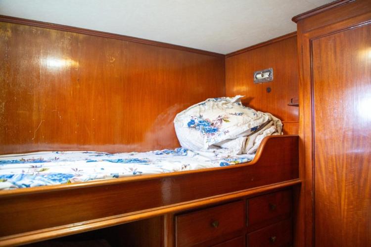 Cozy wooden cabin interior of 1972 Benetti 33 yacht with floral bedding.