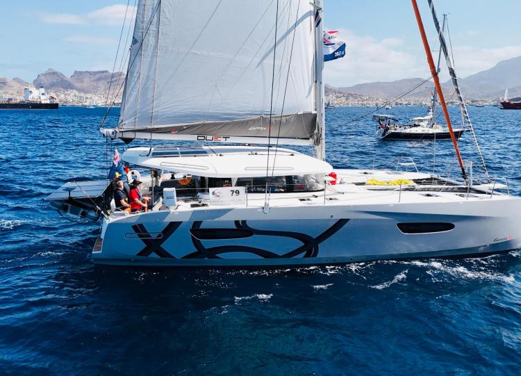 2024 Excess 14 catamaran sailing on blue ocean with crew onboard.