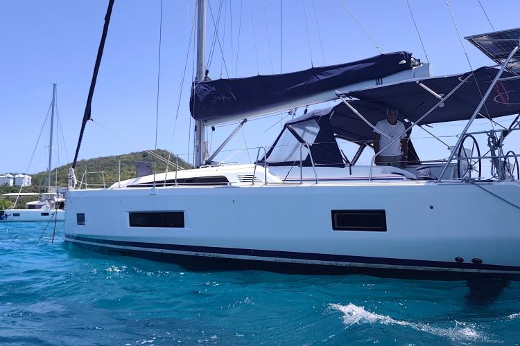 2019 Beneteau Oceanis 46.1 sailboat on turquoise water, with a person onboard.