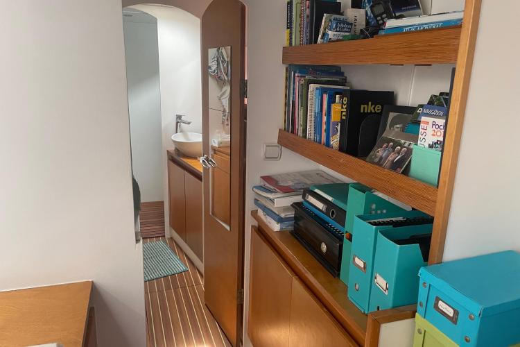 Compact boat interior with bookshelves, storage, and a small bathroom. Custom KSENIA 149, 2010 model.