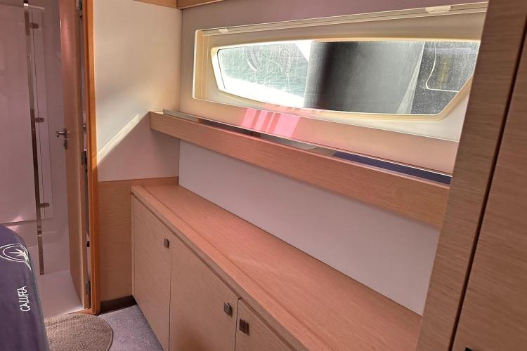 Interior of 2016 Fountaine Pajot Ipanema 58 yacht, featuring sleek wood cabinetry and window.