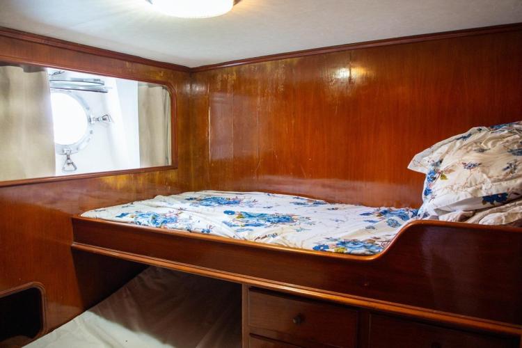 Cozy cabin interior of 1972 Benetti 33 yacht with wooden paneling and floral bedding.