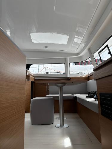 2024 Excess 11 yacht interior with modern seating and table, featuring sleek wood finishes.
