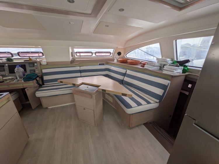 Interior of 2012 Catana 55 yacht with striped seating and wooden table.
