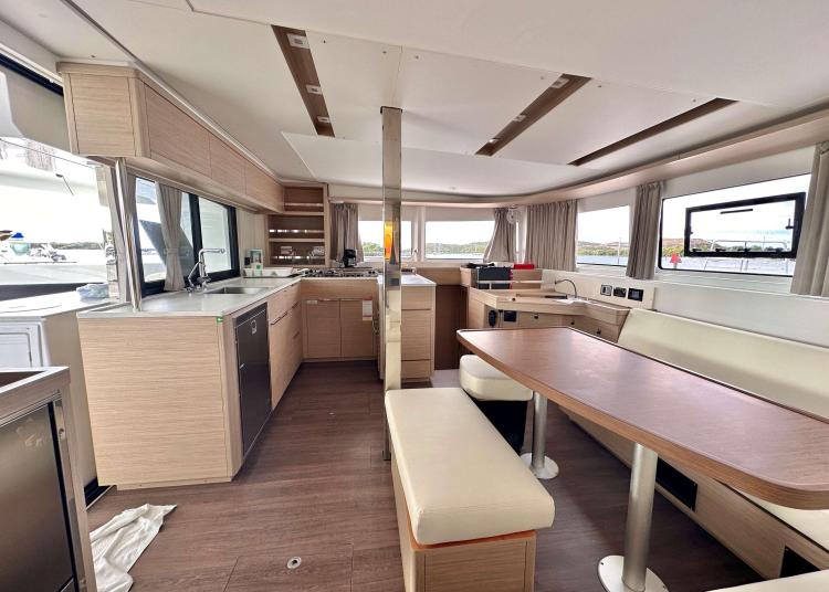 Interior of 2023 Lagoon 46 yacht, featuring modern kitchen and dining area with panoramic windows.