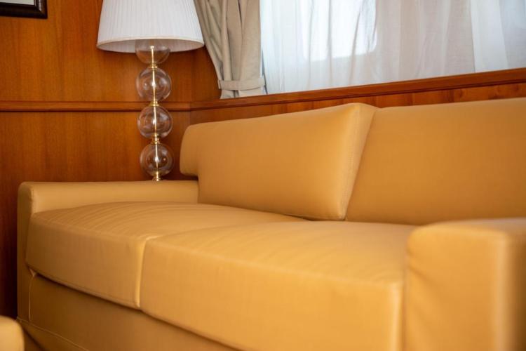 Luxurious interior of 1972 Benetti 33 yacht with beige sofa and elegant lamp.