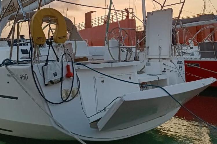 2017 Dufour 460 Grand Large yacht docked at sunset, featuring open transom and safety equipment.