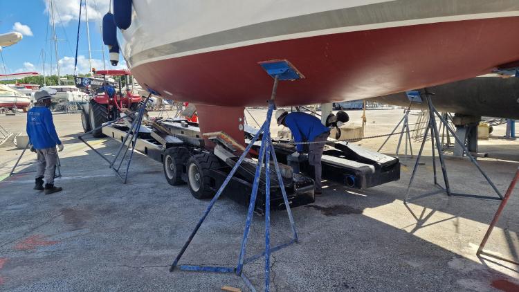 Workers inspecting Elan Impression 434 yacht on trailer in a boatyard.