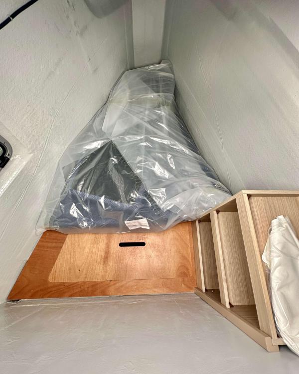Interior view of 2023 Lagoon 46 yacht storage area with wooden flooring and covered items.