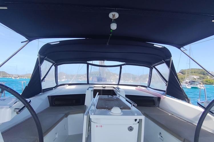 2019 Beneteau Oceanis 46.1 cockpit with canopy, anchored in a scenic bay.