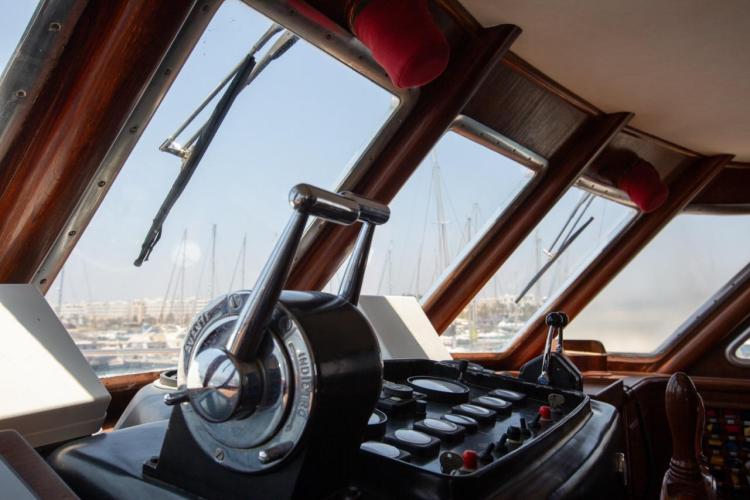Cockpit view of 1972 Benetti 33 yacht with vintage controls and marina backdrop.