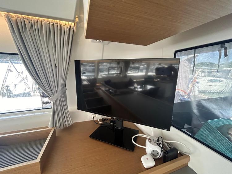 2024 Excess 14 yacht interior with TV, wooden desk, and curtains.