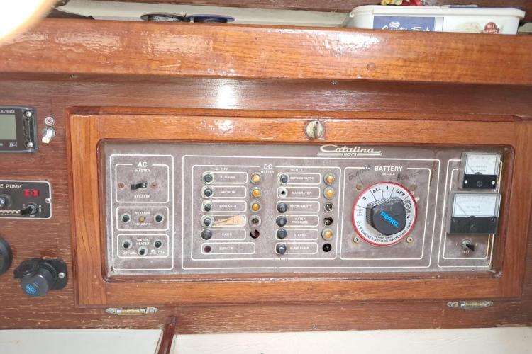 Electrical control panel of a 1986 Dufour Catalina yacht, featuring AC and DC switches.