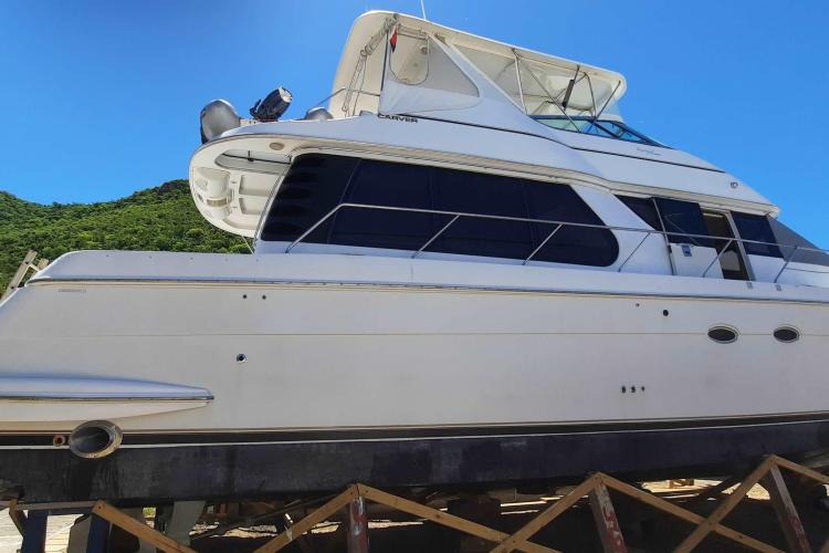 2000 Carver 530 Voyager Pilothouse yacht on dry dock under clear blue sky.