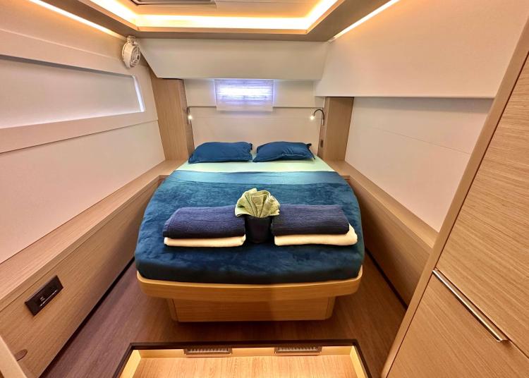 Luxurious cabin interior of 2023 Lagoon 46 yacht with cozy bed and modern lighting.