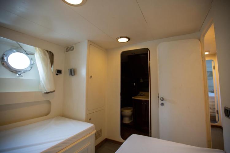 Interior cabin of 1972 Benetti 33 yacht with porthole and ensuite bathroom.