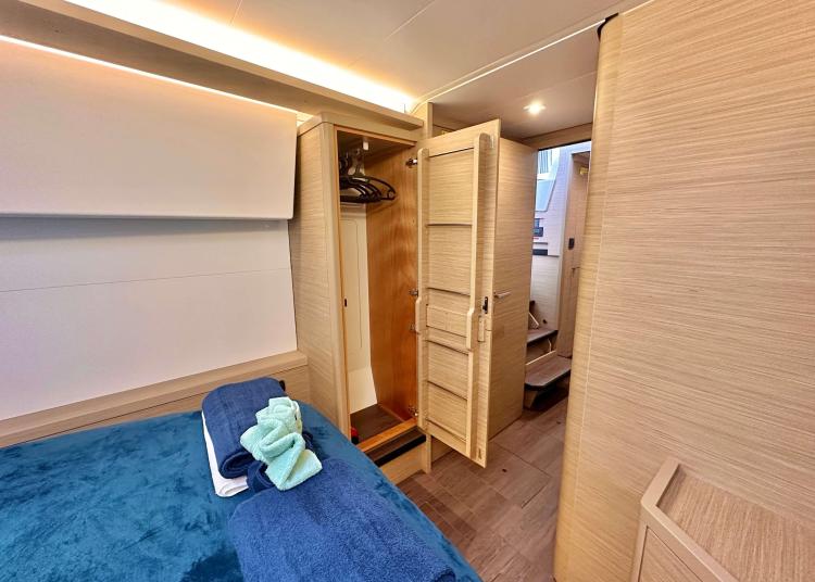 2023 Lagoon 46 yacht interior with cozy bedroom, wooden wardrobe, and modern design.