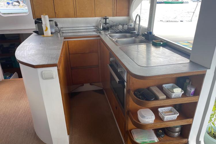 Compact boat kitchen with wooden cabinets, dual sinks, and organized shelves on a Custom KSENIA 149 model.